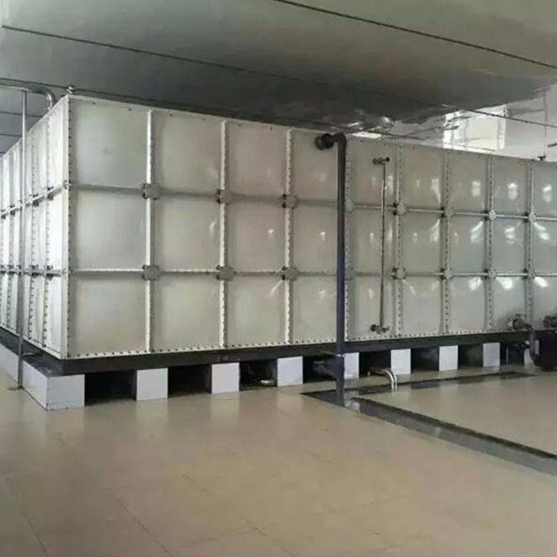 Industrial water storage tanks with structured panel systems and pipe connections under blue sky